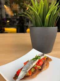 Plato de tapa gourmet presentado en mesa con decoración vegetal