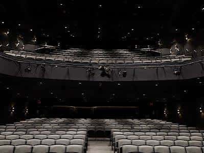 Interior del auditorio principal con butacas grises y escenario oscuro