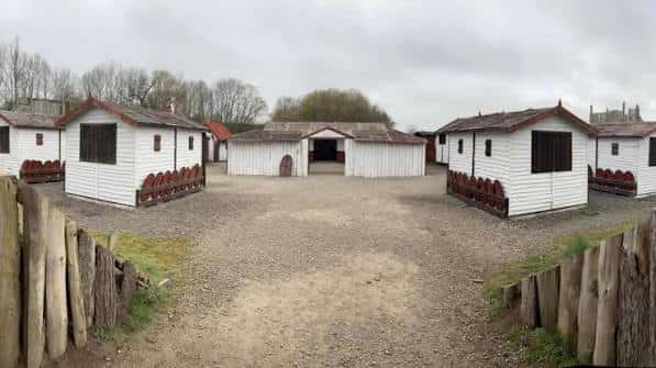 Recreación histórica de cabañas blancas en un patio de tierra