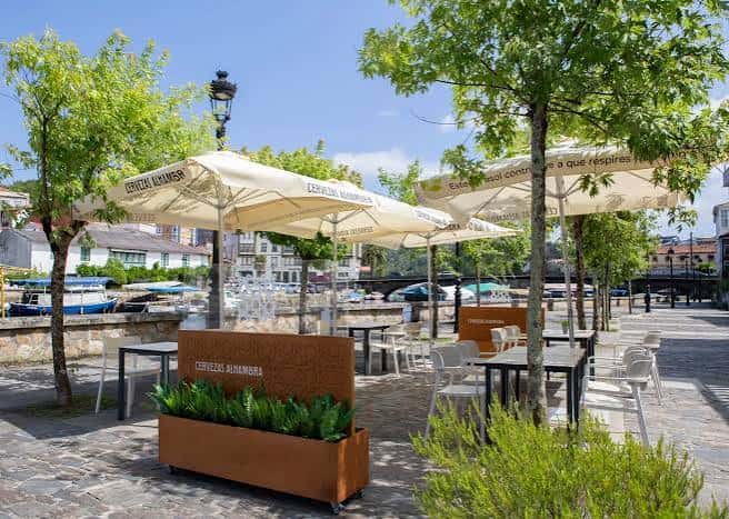 Terraza exterior del restaurante con mesas y sombrillas junto al río