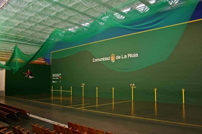 Interior del frontón mostrando la cancha y gradas vacías