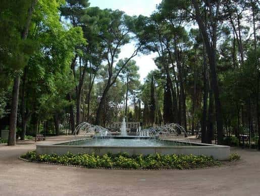 Vista de la plaza con fuente y árboles en un entorno natural