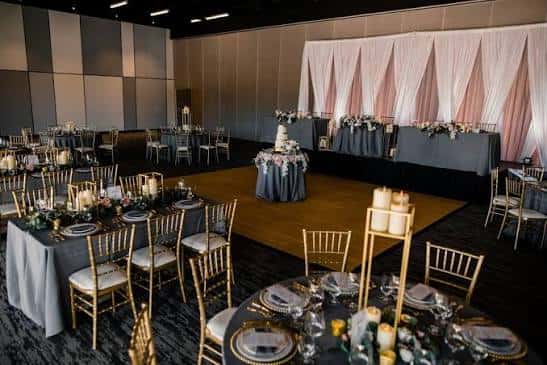 Interior del salón de eventos decorado para una boda con mesas redondas y cortinas rosas