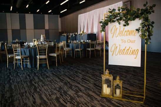 Detalle de la entrada al evento con letrero 'Welcome To Our Wedding' y decoración floral