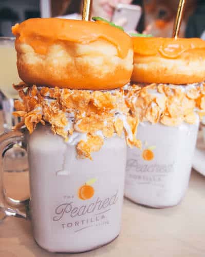 Detalle de un batido decorado con donas y cereales en vaso con el logo del restaurante