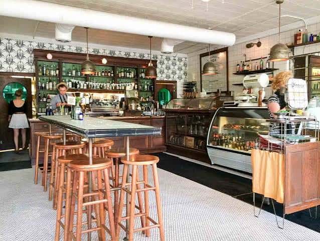 Interior del bar de Hillside Farmacy con estanterías de botellas y taburetes