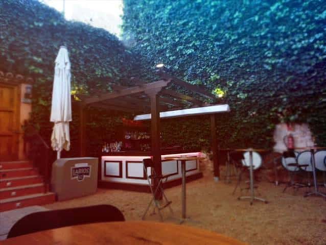 Bar exterior en el patio con estructura de madera y decoración vegetal