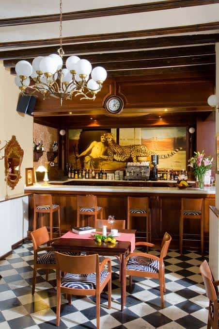 Interior del bar del hotel con decoración clásica, suelo a cuadros y barra de madera