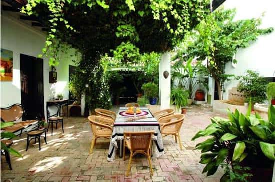 Patio interior ajardinado con mesa para eventos y vegetación exuberante