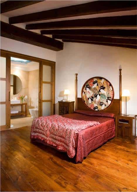 Habitación boutique con cama de cuatro postes, vigas de madera y decoración artística