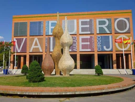 Plaza frontal del centro con escultura abstracta y césped