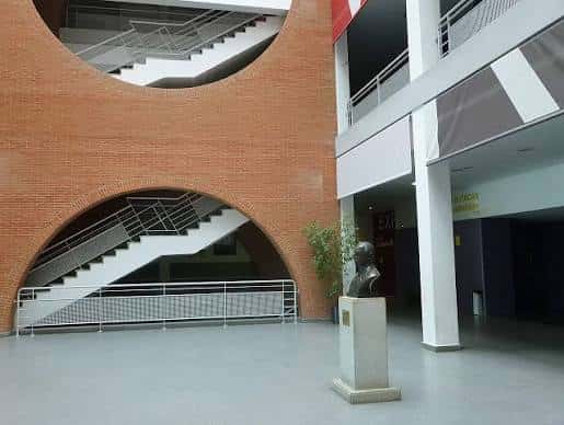 Interior del vestíbulo con escalera de ladrillo y busto