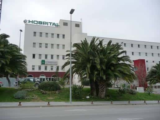 Fachada principal del hospital con letrero 'HOSPITAL' y jardines frontales