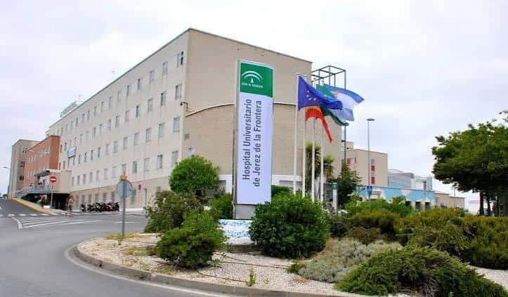 Entrada del hospital con cartel oficial y banderas ondeando