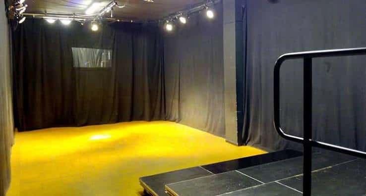Escenario vacío con iluminación amarilla y cortinas negras