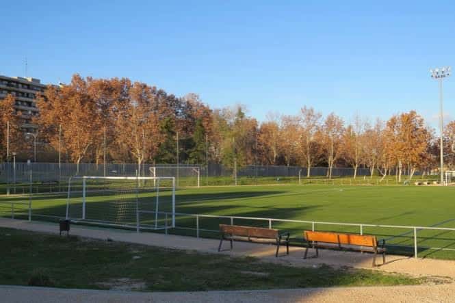 Campo de entrenamiento con portería y bancos en primer plano