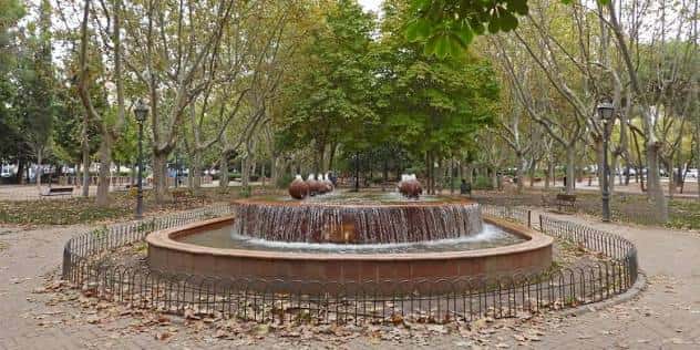 Fuente central del parque rodeada de árboles y senderos, ideal para eventos al aire libre