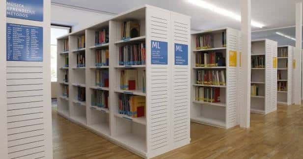 Interior de la biblioteca mostrando estanterías blancas organizadas y amplias para consulta musical
