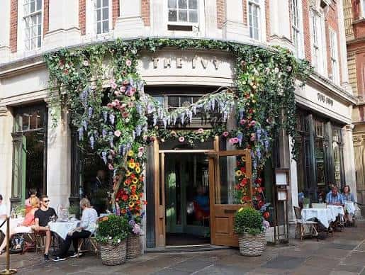 Fachada de The Ivy St Helen's Square en York con decoración floral y clientes en terraza
