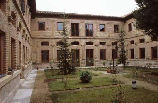 Patio interior del convento con jardines, árboles jóvenes y galerías de arcos de ladrillo