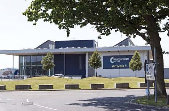 Área de llegadas del aeropuerto con árboles y señalización clara
