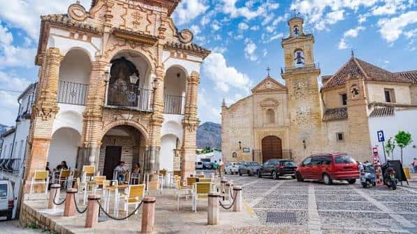 Vista panorámica de la plaza frente a la iglesia, mostrando el pórtico barroco y el edificio religioso en Antequera