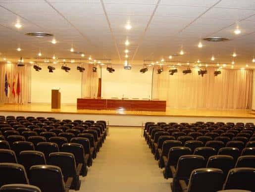 Sala de conferencias con escenario y butacas listas para un evento
