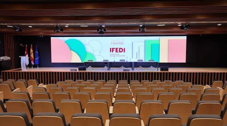 Auditorio moderno con pantalla gigante mostrando el logo IFEDI