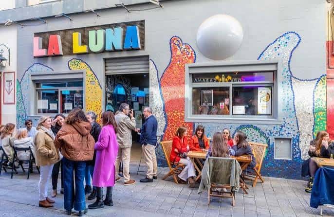 Vista exterior del Bar La Luna con su característica fachada de mosaicos y gente en la terraza