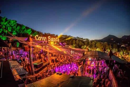 Escenario al aire libre durante un evento con luces de colores y multitud