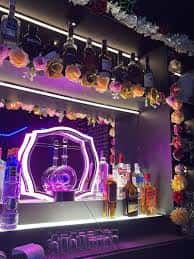 Bar principal del club con botellas decorativas y luces neón