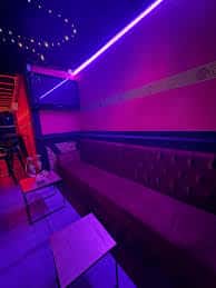 Zona de lounge con sofás y iluminación ambiental en tonos morados