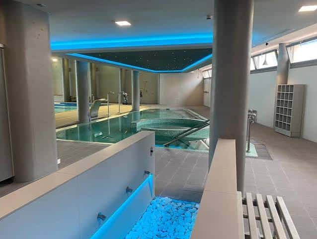 Interior de la piscina climatizada del club con iluminación azul y zona de hidromasaje