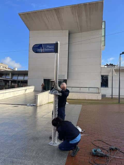 Instalación del cartel de la plaza frente al edificio moderno