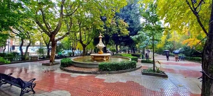Fuente central del Paseo de Cánovas rodeada de árboles y bancos