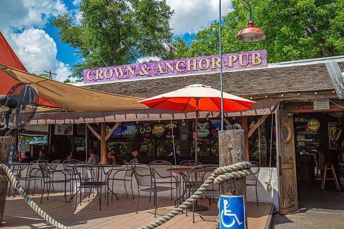 Vista exterior del Crown & Anchor Pub mostrando su terraza con toldos y mesas al aire libre