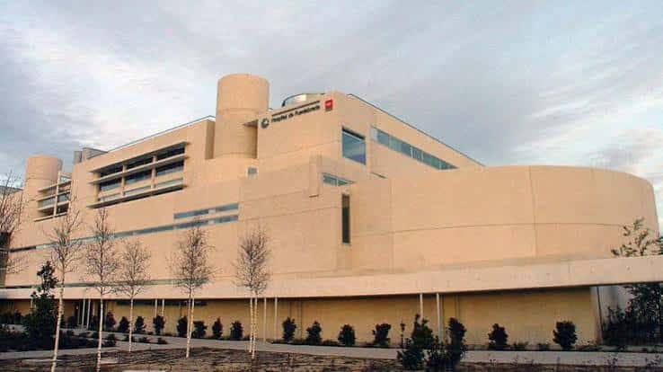 Fachada principal del hospital en tonos beige bajo cielo nublado