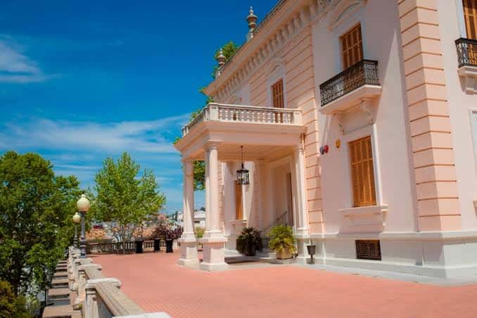 Entrada principal del palacio con columnas y porche bajo cielo azul