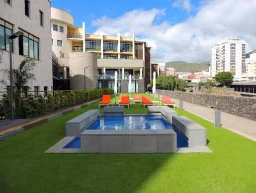 Piscina elevada con césped artificial y vistas a la ciudad