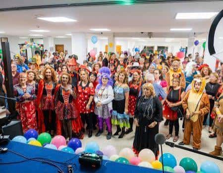 Evento comunitario interior con participantes disfrazados y decoración festiva