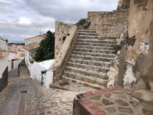 Escalera de piedra junto a murallas antiguas con vistas al pueblo