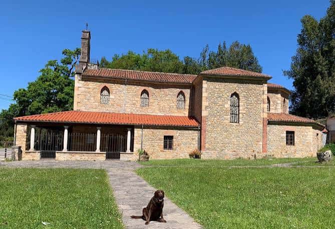 Iglesia de San Salvador rodeada de césped bajo un cielo azul despejado