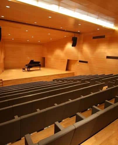 Interior del auditorio con escenario de madera y piano