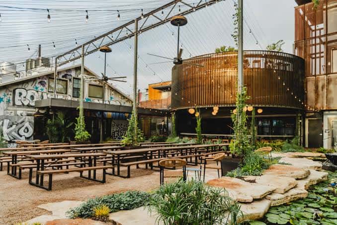 Patio vacío con mesas largas y estructura metálica iluminada