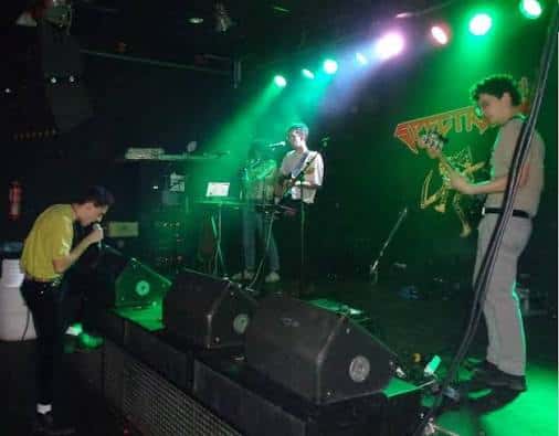 Banda actuando en el escenario con iluminación verde y público cerca