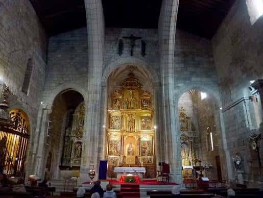 Interior de la iglesia mostrando el altar mayor dorado y las columnas de piedra