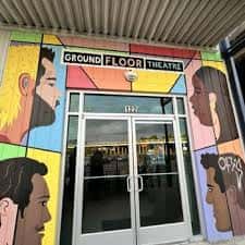 Fachada frontal del teatro con mural colorido de rostros artísticos sobre la entrada