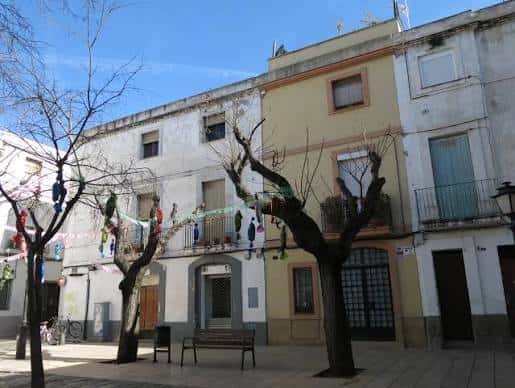 Plaza decorada con adornos festivos colgados entre los árboles bajo un cielo azul