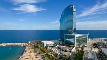 Exterior del W Barcelona en día soleado, mostrando la playa y el edificio desde una perspectiva elevada