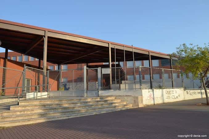 Entrada lateral del instituto con escaleras y estructura metálica bajo cielo despejado